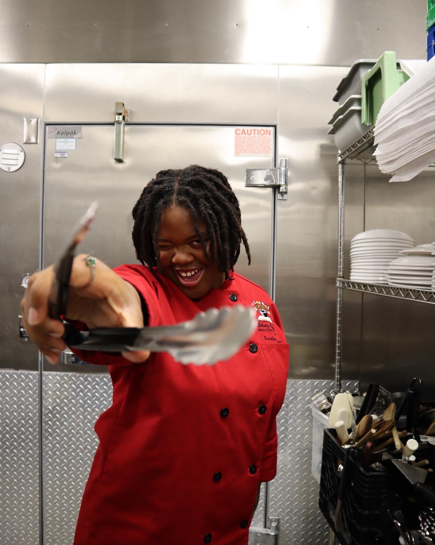 chef holding tongs in professional kitchen